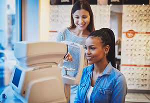 Optometrist and patient using an eye examination machine in an eyewear store