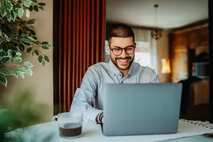 Man sitting at a desk with a laptop and a cup of coffee