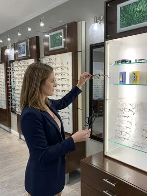 A woman is looking at eyeglasses on display in a store