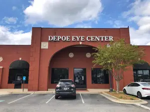 A red building with a sign reading Depo Eye Center, with a black car parked in front