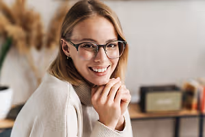 A smiling woman wearing glasses in an indoor area