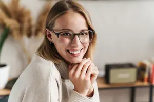 A smiling woman wearing glasses in an indoor area
