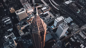 Aerial view of a city with tall buildings, roads, and a golden-colored skyscraper in the center.