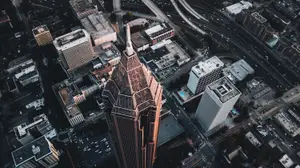Aerial view of a city with tall buildings, roads, and a golden-colored skyscraper in the center.