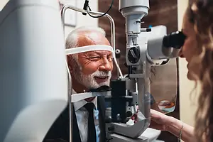 Senior man getting an eye examination by a female optician