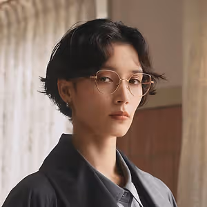 A woman with short hair and glasses standing in front of a white curtain.