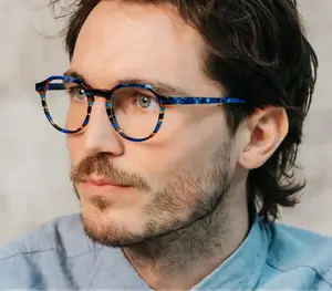 A man with a beard is wearing glasses with a blue frame.