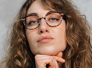 A woman with curly brown hair wearing round glasses with multicolored frames