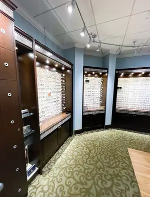 An indoor room that is possibly a shop with a wooden floor and ceiling lights and displays of eyeglasses and other items