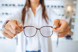 A woman holding a pair of eyeglasses
