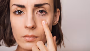 Close-up of a woman's face with her finger on her eye