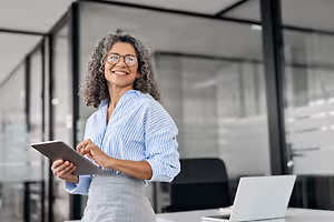 woman in an office room holding a tablet and smiling