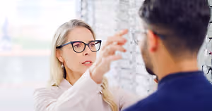 A woman and a man looking at eyeglasses in a store