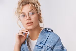 Woman with blonde hair wearing glasses and a denim jacket.