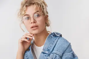 Woman with blonde hair wearing glasses and a denim jacket.