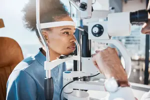 An eye doctor examining a female patient's eye with a slit lamp