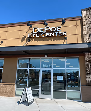 The front entrance of DePoe Eye Center is pictured with a sign indicating that they are open