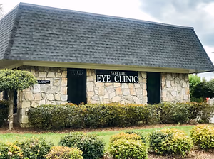 An image of the front of the Fayetteville Eye Clinic with gray shingles and a stone wall.