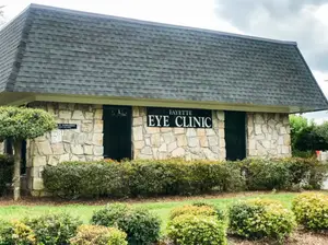 An image of the front of the Fayetteville Eye Clinic with gray shingles and a stone wall.