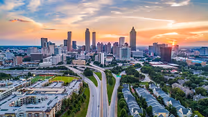 A breathtaking aerial view of a city skyline at sunset, with tall buildings and a highway stretching into the distance