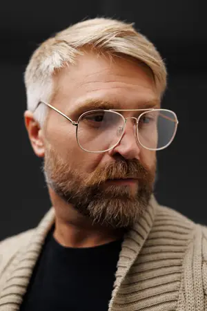A man with a beard wearing glasses and a sweater