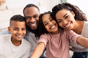 A family of four is smiling at the camera in a room