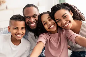 A family of four is smiling at the camera in a room