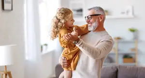 An older man holding a young girl while giving a thumbs up sign