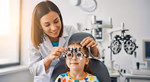 A woman doctor is checking a young girl's vision in an office.