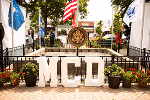 A photo of the MCI sign with flags and trees in the background