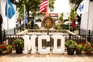 A photo of the MCI sign with flags and trees in the background
