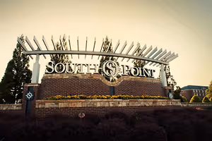 A sign for South Point, featuring a brick wall with yellow flowers and a metal arch