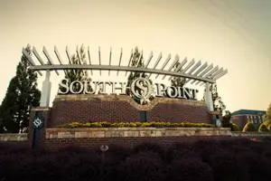 A sign for South Point, featuring a brick wall with yellow flowers and a metal arch