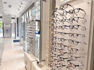 A shop displaying many glasses on the wall with white walls and tiled floors