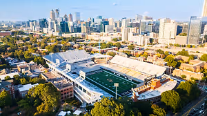 Aerial view of a college football stadium surrounded by trees and buildings in a city
