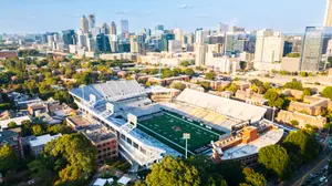 Aerial view of a college football stadium surrounded by trees and buildings in a city