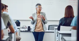 A woman teacher explaining a molecular model to students in a classroom.