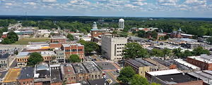 Aerial view of a cityscape with many buildings, trees, and a clear blue sky.
