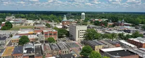 Aerial view of a cityscape with many buildings, trees, and a clear blue sky.