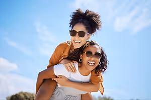 Two women smiling and posing for a photo on a sunny day