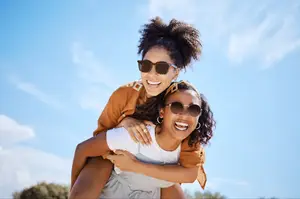 Two women smiling and posing for a photo on a sunny day