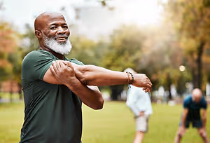 An older man stretching his arm in a park