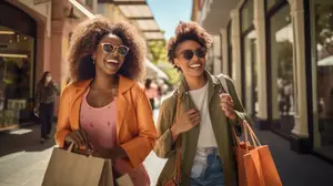 Two women walking down the street while carrying shopping bags and smiling