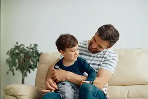 A man in a striped shirt holding a smiling child on his lap
