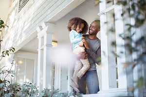 A man holding a child in his arms on the porch of a house