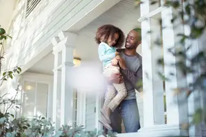 A man holding a child in his arms on the porch of a house
