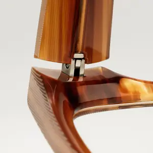 A close-up view of the back of a chair with a curved, wooden seat and a metal hinge, the chair's frame is made of wood with a smooth finish, possibly made of horn, and the metal hinge is attached to the back of the chair, the chair's seat has a curved design with a smooth finish, possibly made of horn, the chair's frame is made of wood with a smooth finish, possibly made of horn, and the metal hinge is attached to the back of the chair.