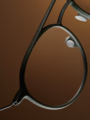 Close up of an eyeglass frame with dark brown color and reflective lens