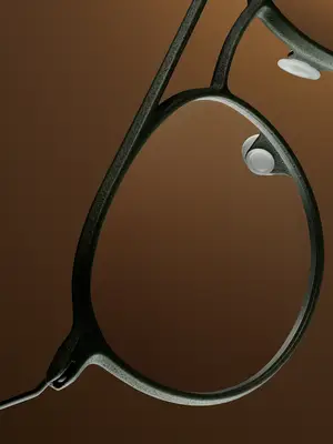 Close up of an eyeglass frame with dark brown color and reflective lens