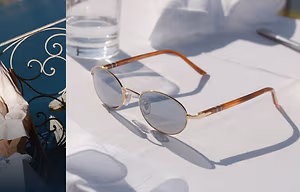 Image of sunglasses and a person wearing a white dress near a water body